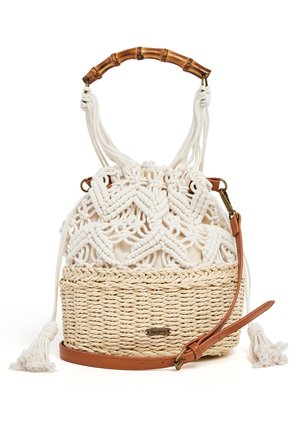 Met de hand geweven beige strooien emmertas met witte macramé bovenkant, bamboe handvat en afneembare bruine leren schouderriem, kwastdetails aan de zijkanten.