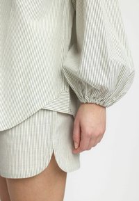Gestreifter Baumwoll-Pullover mit Puffärmeln und abgerundetem Saum, kombiniert mit passender Shorts mit abgerundeten Seitenschlitzen.