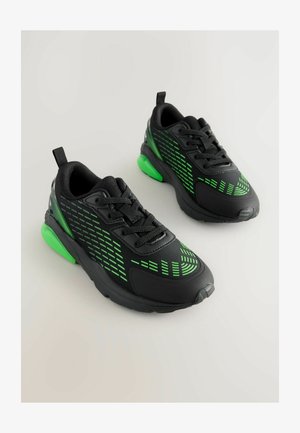 Zapatillas deportivas negras con acentos verdes, que cuentan con un upper texturizado con un patrón geométrico, puntera redondeada y un talón acolchado.