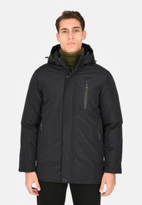 Parka nera isolata con tasca sul petto con cerniera, due tasche laterali, cappuccio e finitura liscia opaca. Foderata con un dolcevita verde a coste.