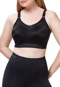 Svart sportbehå med slät tyg och ett nätpanel upptill, med justerbara axelband och en bred underbande för stöd.