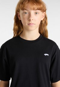 Černé bavlněné tričko s kulatým výstřihem a krátkými rukávy. Na levé straně hrudníku se nachází malá bílá grafika s skateboardem.
