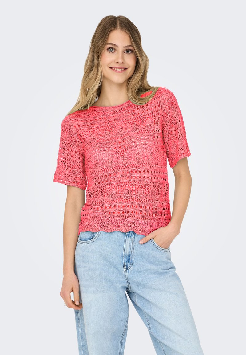 Rosa, gehäkeltes Kurzarmoberteil mit gewellten Saum und unterschiedlichen offenen Mustern, getragen über hellblauen Denim-Jeans.