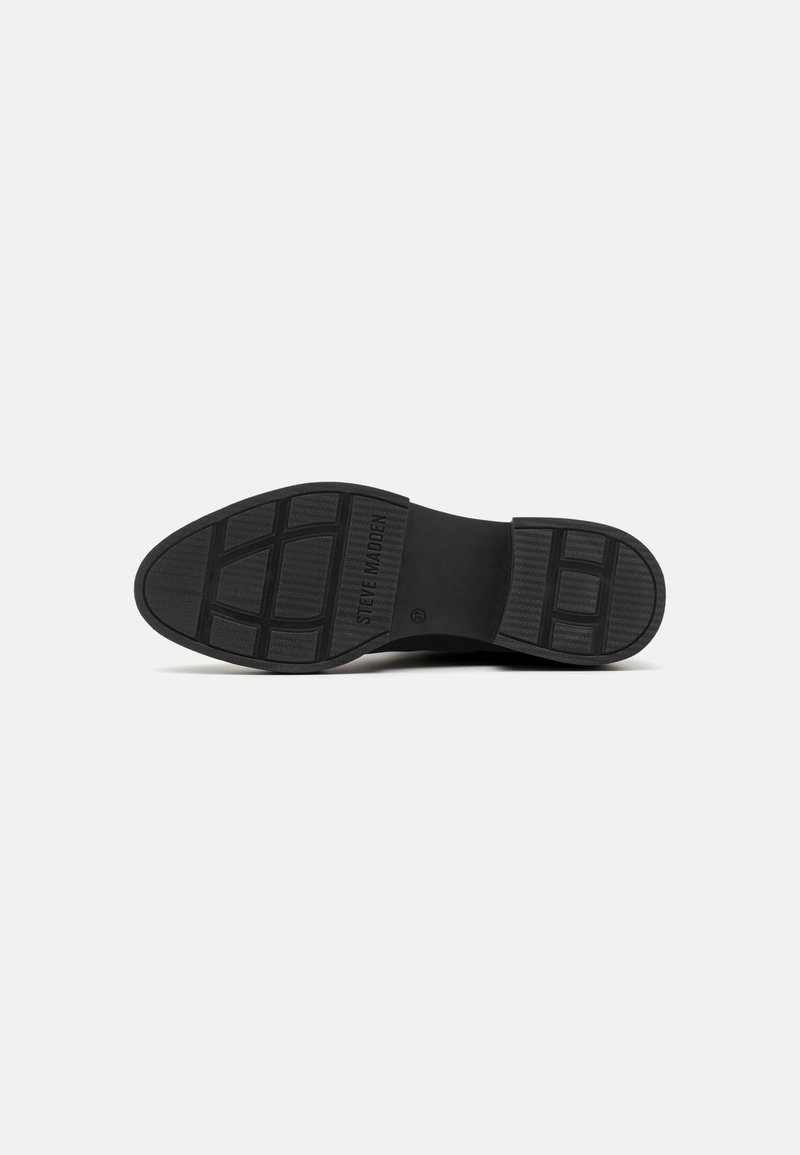 Schwarze Sohle eines Steve Madden Schuhs mit strukturierten Profilmustern und dem eingravierten Markennamen in der Nähe der Mitte.