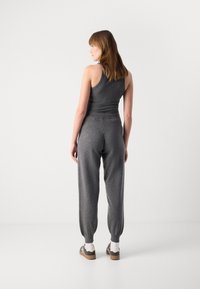 Grå tank topp og joggesett, med en tettsittende design, myk stoff, elastisk midje og smale mansjetter. Detaljer inkluderer kontrasterende fottøy.