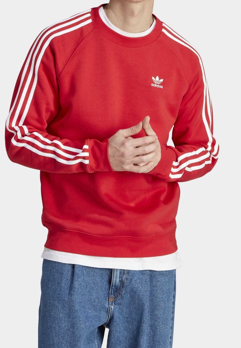 Felpa rossa con strisce diagonali bianche sulle maniche, collo e orlo a coste, con un piccolo logo bianco sul petto. Vestibilità casual.