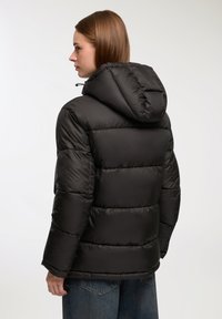 Czarna kurtka puchowa z kapturem, z obszytymi sekcjami i elastycznymi mankietami. Gładka, błyszcząca tekstura z lekko luźnym krojem.