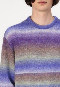 Pull en tricot avec un col rond, présentant des rayures horizontales dans des nuances de bleu, violet et marron ; tissu en laine texturé.