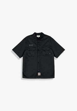 Zwart overhemd met korte mouwen en knopen, voorzien van twee klepzakken op de borst, een klein label op de linkerzak, Aziatische tekens op de rechterborst en een label aan de zoom.