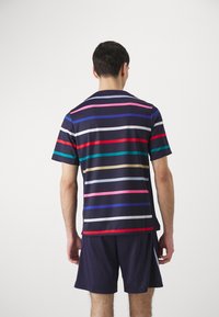 Košile s krátkým rukávem v námořnické modři s vodorovnými pruhy v červené, růžové, zelené a bílé. Má kulatý výstřih a volnější střih.