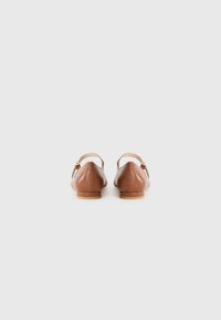 Bruine leren balletschoenen met een ronde neus, een achterkantstrap en een klein goudkleurig hardwareaccent. Glad oppervlak en platte zool.