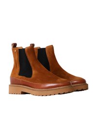 Botas Chelsea de ante en marrón con paneles elásticos laterales negros, un ribete de cuero marrón y una suela de goma gruesa con borde dentado.
