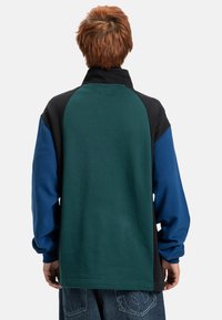Sweatshirt em blocos de cor com painéis verde, preto e azul. Tecido suave, design de gola alta e mangas longas com punhos canelados.