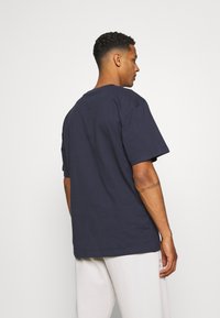 Camiseta de manga corta en color azul marino, con cuello redondo, hecha de algodón, que presenta un corte relajado y una textura suave.