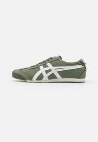 Zapatillas deportivas verdes con acentos blancos, tejido texturizado, puntera redonda y suela de goma plana. Presentan cierre con cordones y etiqueta trasera para facilitar el calzado.