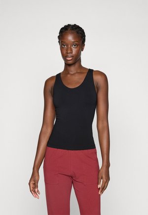 Black fitted tank top with wide straps and a rounded neckline, paired with maroon cargo pants, creating a casual look. Smooth texture.