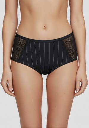 Biancheria intima da donna nera a vita alta con righe verticali e pannelli in pizzo su entrambi i lati, indossata da una persona in piedi su uno sfondo semplice.