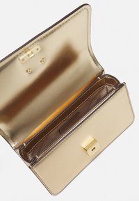 Gouden portemonnee met een gladde, metalen afwerking, voorzien van een sluiting met klip en meerdere vakken, waaronder een pasjesvak en een binnenvak.