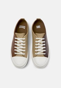 Zapatillas con una parte superior de cuero suave en colores marrón, beige y caqui, cordones blancos y suela de goma. Presentan una puntera redondeada y el logo de la marca.