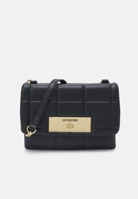 Borsa a tracolla nera in ecopelle trapuntata con una placca logo in tonalità oro e tracolla rimovibile, caratterizzata da una forma rettangolare e una texture liscia.