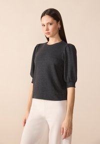 Szary, teksturowany sweter z bufiastymi rękawami i okrągłym dekoltem; ma dopasowany dół i miękki, elastyczny materiał.