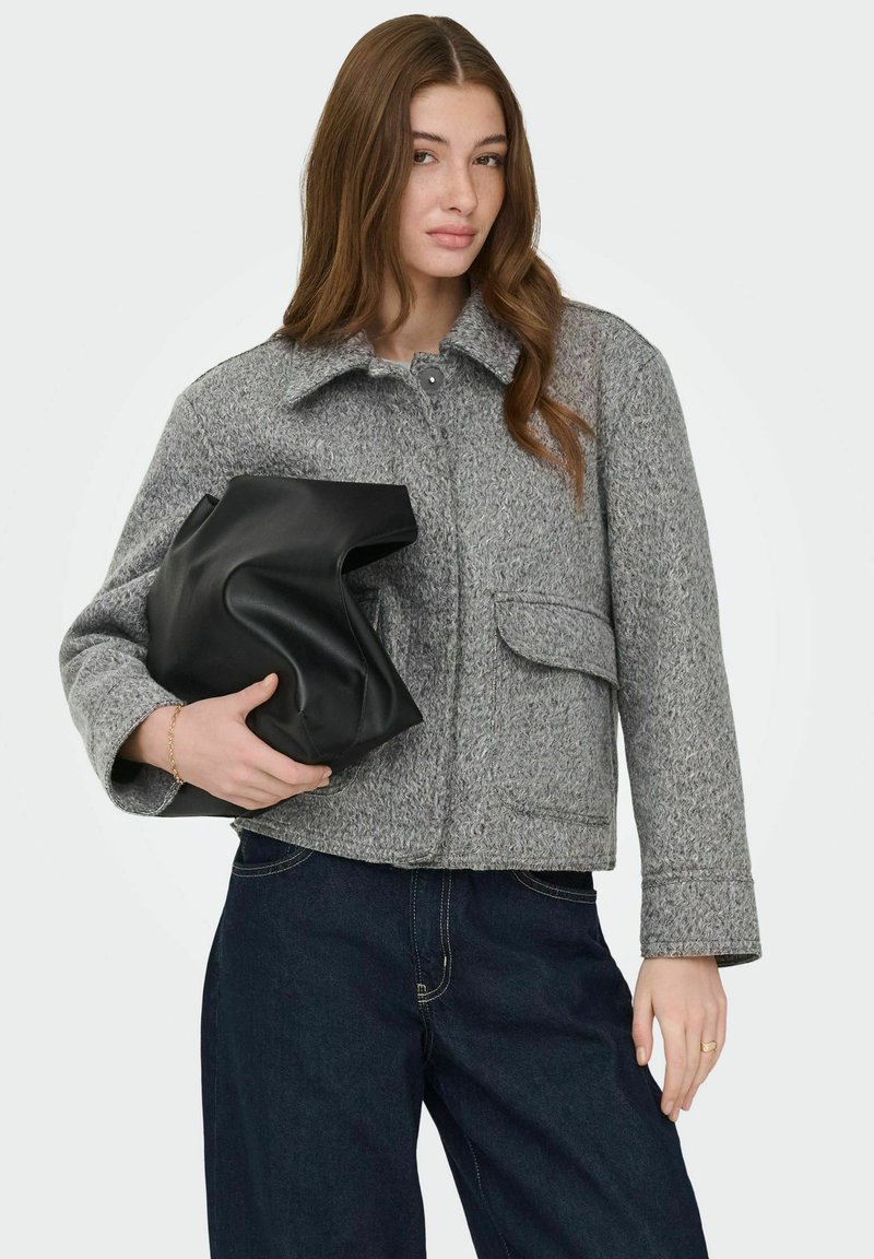 Veste en laine grise avec col à revers, fermeture à boutons et poches avant, associée à un sac en cuir noir et un pantalon en jean foncé.