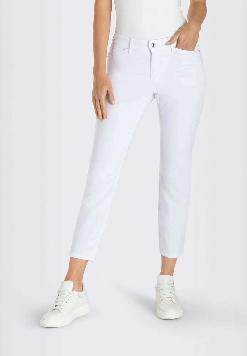 Witte rechtlopende jeans met frontzakken, knoopsluiting en een gladde textuur. Gecombineerd met witte sneakers voor een gecoördineerde look.