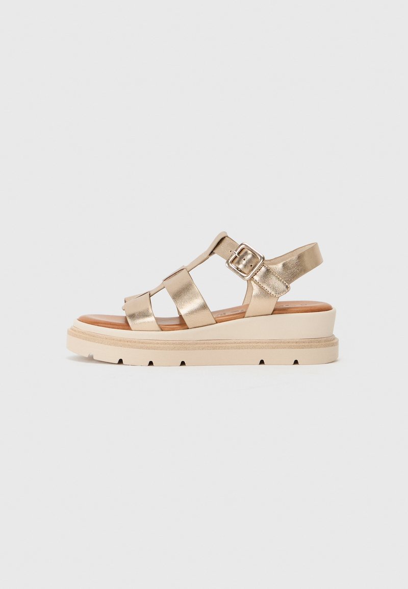 Goldfarbene metallic Leder-Sandale mit dicker, cremefarbener Plateausohle und mehreren Riemen. Sie verfügt über einen Schnallenverschluss für einen sicheren Halt.