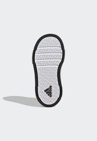 Biała podeszwa tenisówki z wielokierunkowym heksagonalnym wzorem trakcyjnym, wzmocnione czarne gumowe krawędzie, z logo "adidas" w czerni.