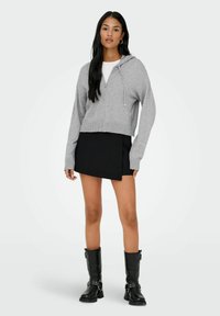 Hallihallitus hall matriksiga kapuutsiga, kombineeritud musta mähkeskleidiga ja mustade põlvikute kõrvaklappidega, millel on lukud.