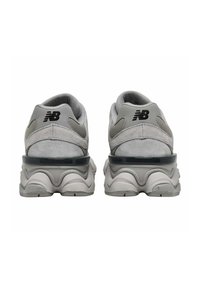 Scarpe da ginnastica grigie con upper texturizzato, design arrotondato e suola ondulata. Presentano un logo nero e dettagli traslucidi sul tallone.