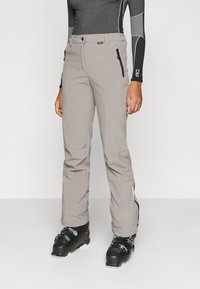 Hallid suusapüksid voolujoonelise disainiga, millel on lukuga taskud ja silekate tekstuur. Ühildatud mustade suusasaabastega talvistes tegevustes.