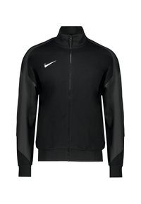 Zwarte Nike trackjack met een volledige rits, hoge kraag, contrasterende stofpanelen en een wit logo op de linkerborst.