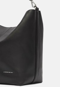 Schwarze Schultertasche aus Leder mit einer geschwungenen Form, ausgestattet mit einem silbernen Metallverschluss, zarter Naht und einem Markenlogo an der Seite.