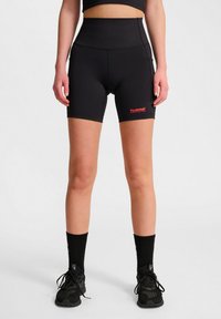 Höga, svarta sportshorts i stretchy tyg, med en röd logotyp på benet och en åtsittande design.