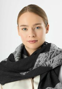 Écharpe noire et grise à motifs en tissu doux, avec des designs élaborés et des bords à franges, drapée lâchement autour du cou.