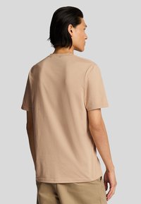 T-shirt in cotone beige con scollo rotondo, maniche corte e vestibilità comoda. Tessuto liscio, dettagli di cucitura minimi sul collo.