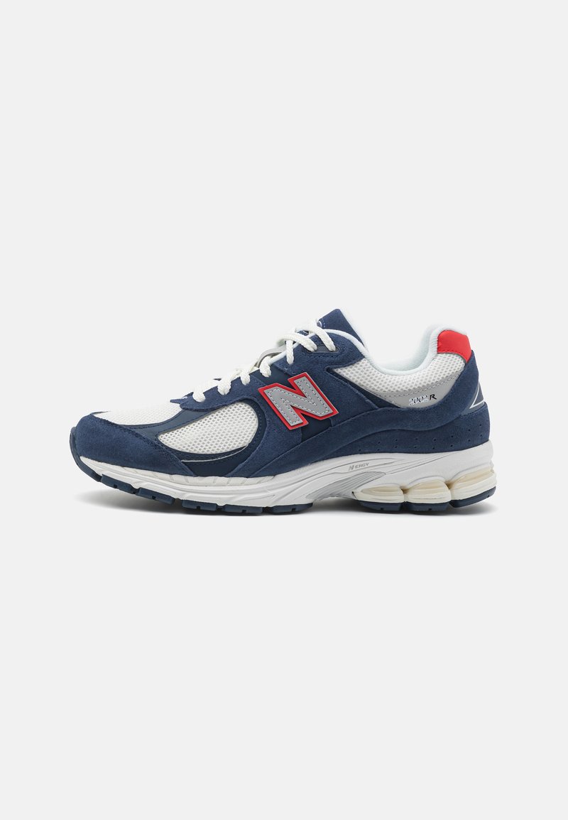 Navy and white athletic shoes with mesh and suede materials, featuring a prominent red New Balance logo and a cushioned sole design.