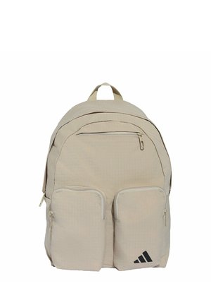 Mochila beige con múltiples compartimentos con cremallera y dos bolsillos frontales, con un logo negro de Adidas en el bolsillo inferior derecho.