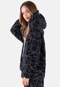 Czarna bluza z kapturem wykonana z miękkiego materiału, z odważnym szarym nadrukiem, oversize'owym krojem i regulowanym kapturem ze sznurkiem.