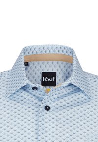 Helles blaues Hemd mit einem sich wiederholenden Fächer-Muster in dunklerem Blau. Verfügt über einen weichen Kragen und eine Knopfleiste an der Vorderseite, mit einem beigen Innenfutter.