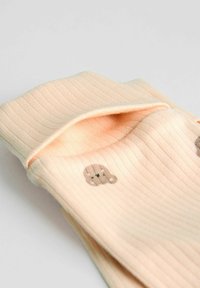 Ribbed peach socks with playful brown bear motifs; soft material with a folded cuff design for added comfort and style.