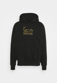 Svart huvtröja i bomullsblandning, med en gul "Karl Kani Jeans" logotyp på bröstet, ribbade manschetter och en känguruficka.