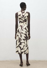 Vestido sin mangas, de longitud hasta la rodilla en crema con atrevidos patrones de hojas marrones. Presenta un corsé ajustado y un diseño de espalda abierta. Tejido suave y ligero.