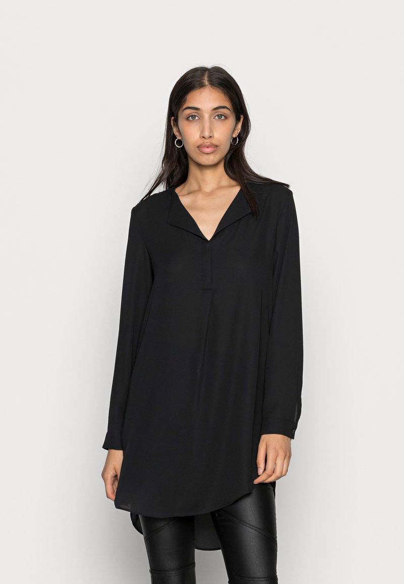 Long-sleeve black tunic made of lightweight fabric, featuring a notched collar, front button detail, and an asymmetrical hemline.