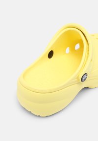 Sabot jaune à enfiler avec bride réglable au talon et trous de ventilation, fabriqué en mousse légère moulée.
