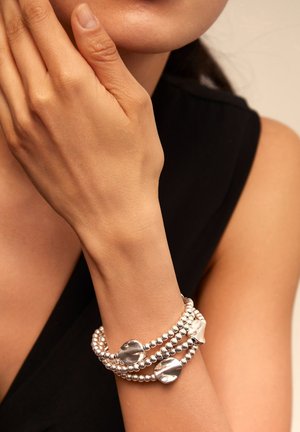 Pulsera de cuentas plateadas con acentos metálicos lisos e irregulares; cuenta con múltiples hilos, creando una apariencia en capas y texturizada.