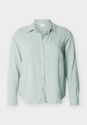 Gaiši zaļa, garām piedurknēm, ar apkakli un divām krūšu kabatām, krekla veida blūze, attēlota pret vienkrāsainu fonu.