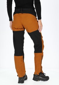 Pantaloni da donna per attività all'aperto in arancione e nero. Realizzati in tessuto resistente all'acqua, con tasche cargo e cerniere sui polsini.