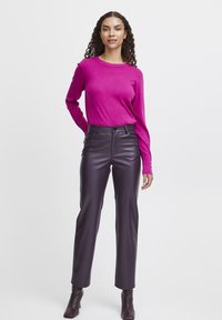 Fuchsia strikket langærmet top parret med højtsiddende, tætsiddende lilla faux læderbukser og matchende ankelstøvler.